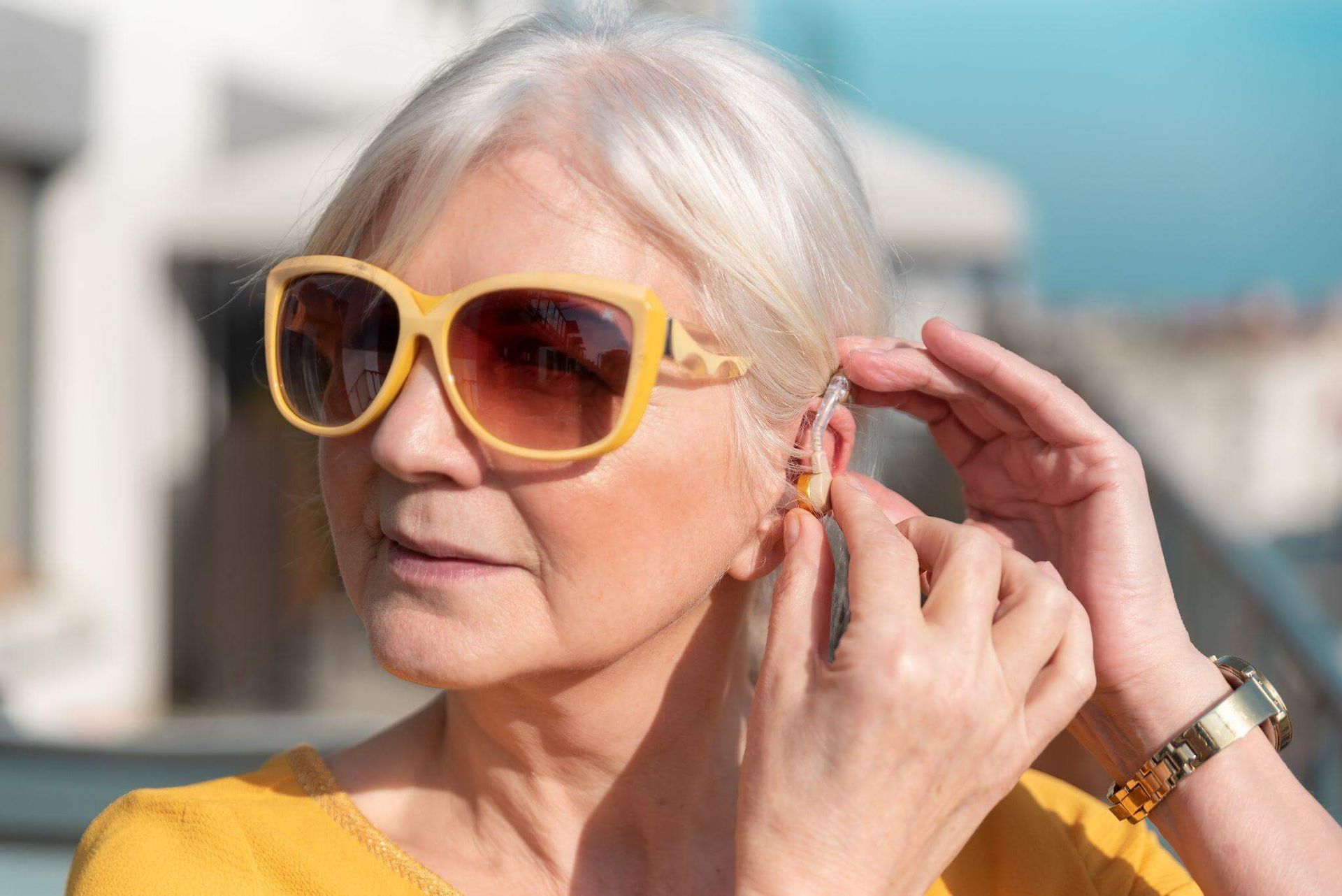 older woman adjusting hearing aid