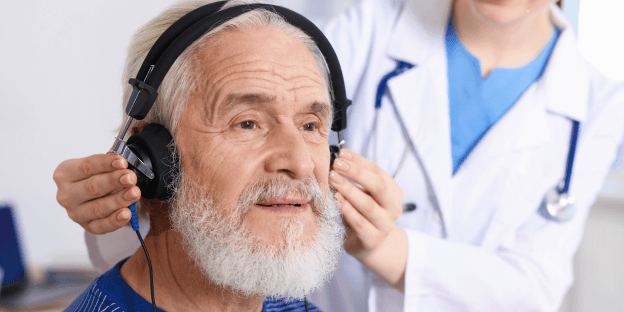 older man receiving hearing evaluation for noise induced hearing loss