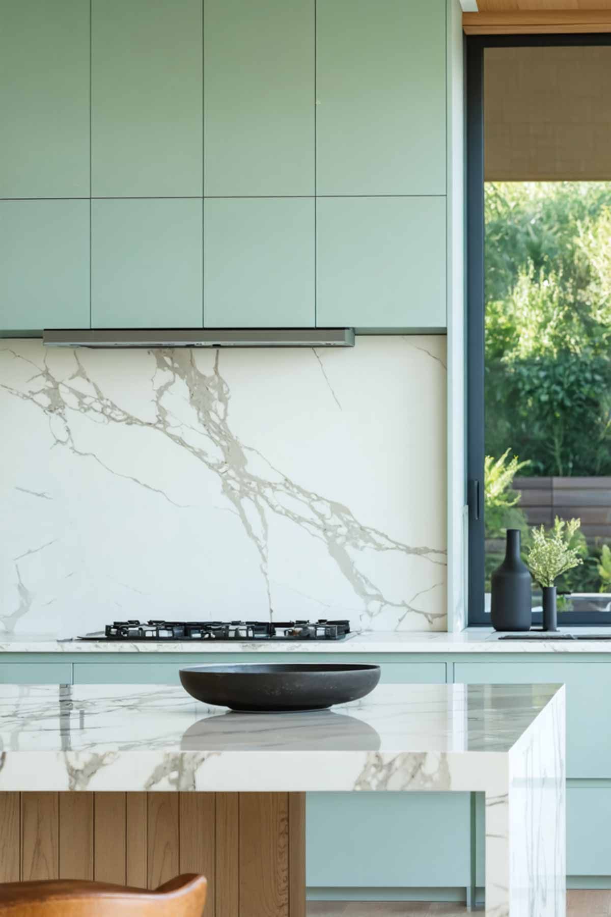A kitchen with green cabinets and a marble counter top.