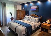 Chambre avec un mur d'accent bleu, des meubles en bois, un lit avec des touches de bleu et un tableau de paysage.