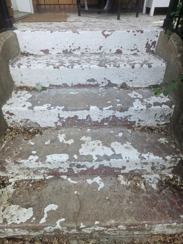 Marches en béton dont la peinture blanche s'écaille.