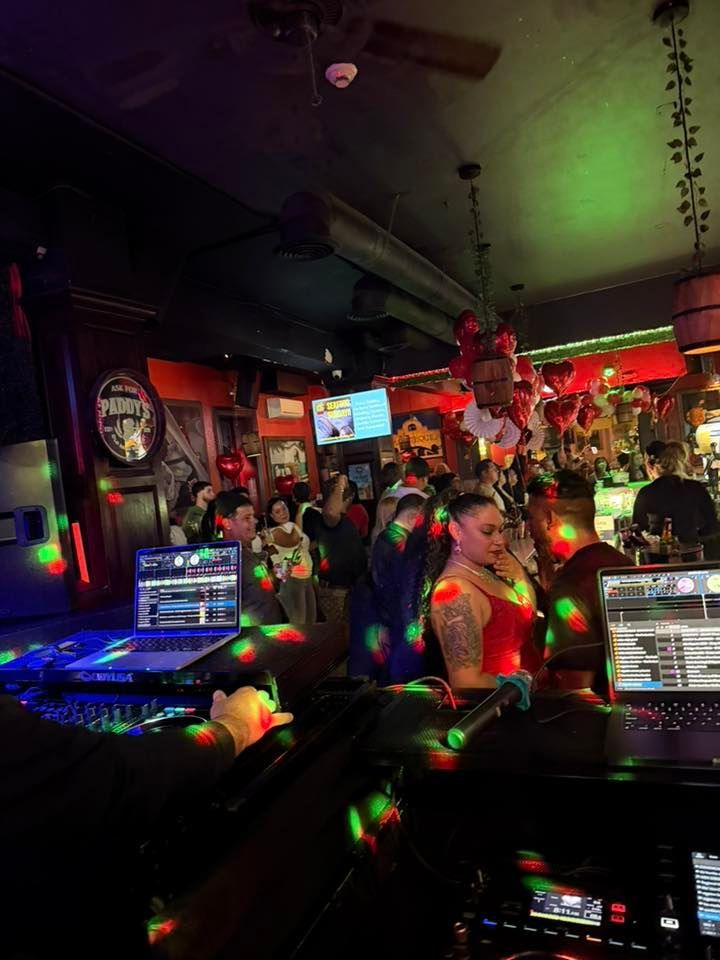 Crowded neon-lit nightclub with people chatting at tables and laptop screens glowing in the foreground