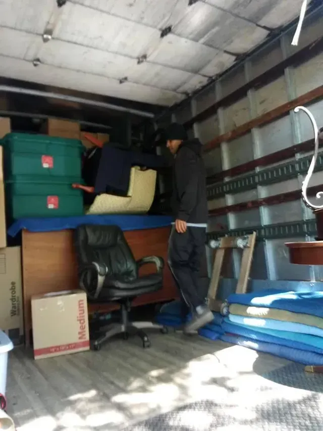 A man in a moving truck with a box that says medium on it
