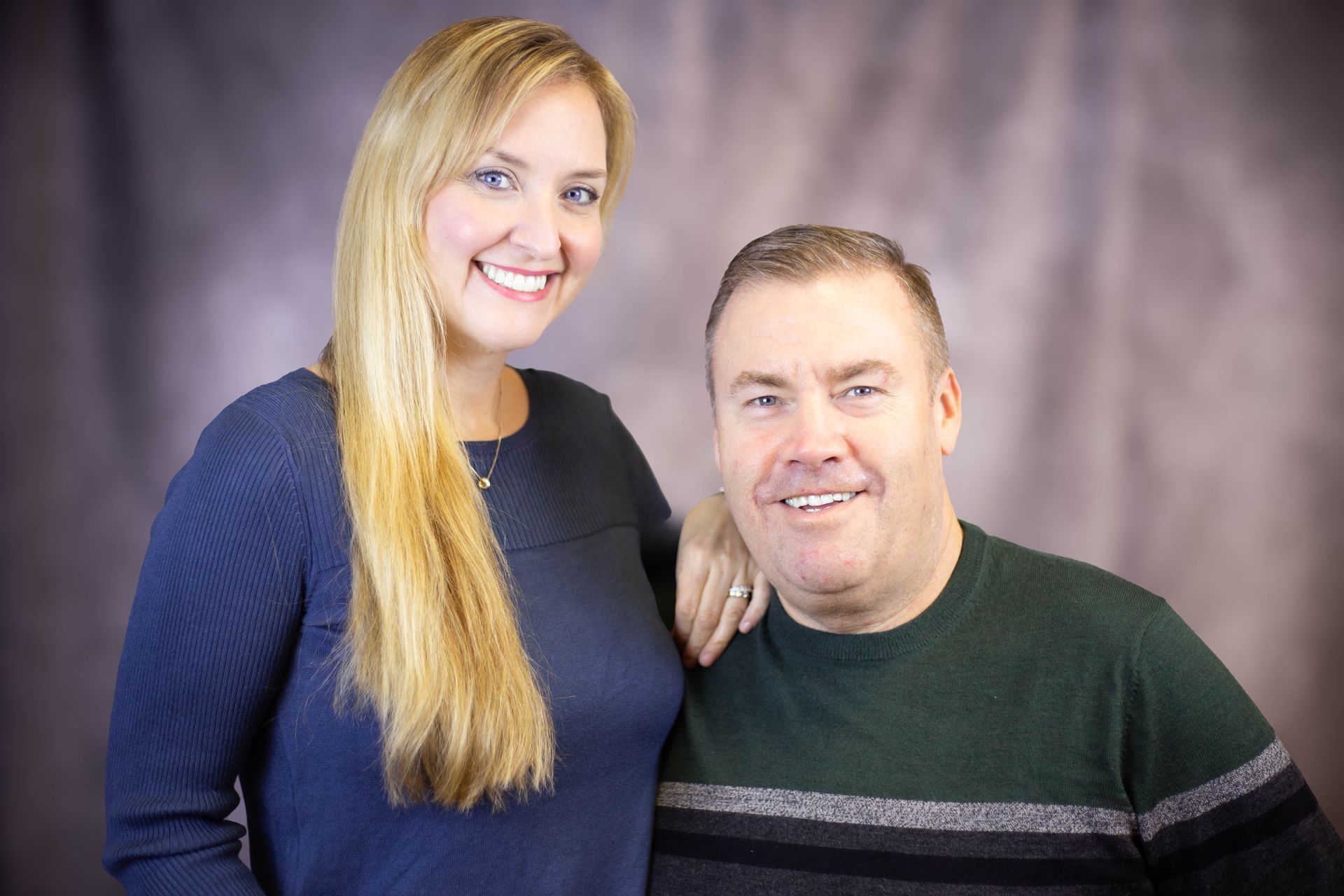 A man and a woman are posing for a picture together and smiling.
