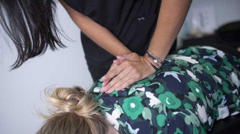 A chiropractor woman is giving a woman an adjustment on her back.