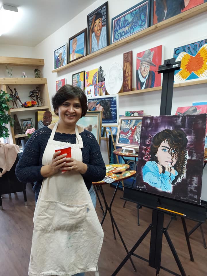 A woman is standing in front of a painting of michael jackson.
