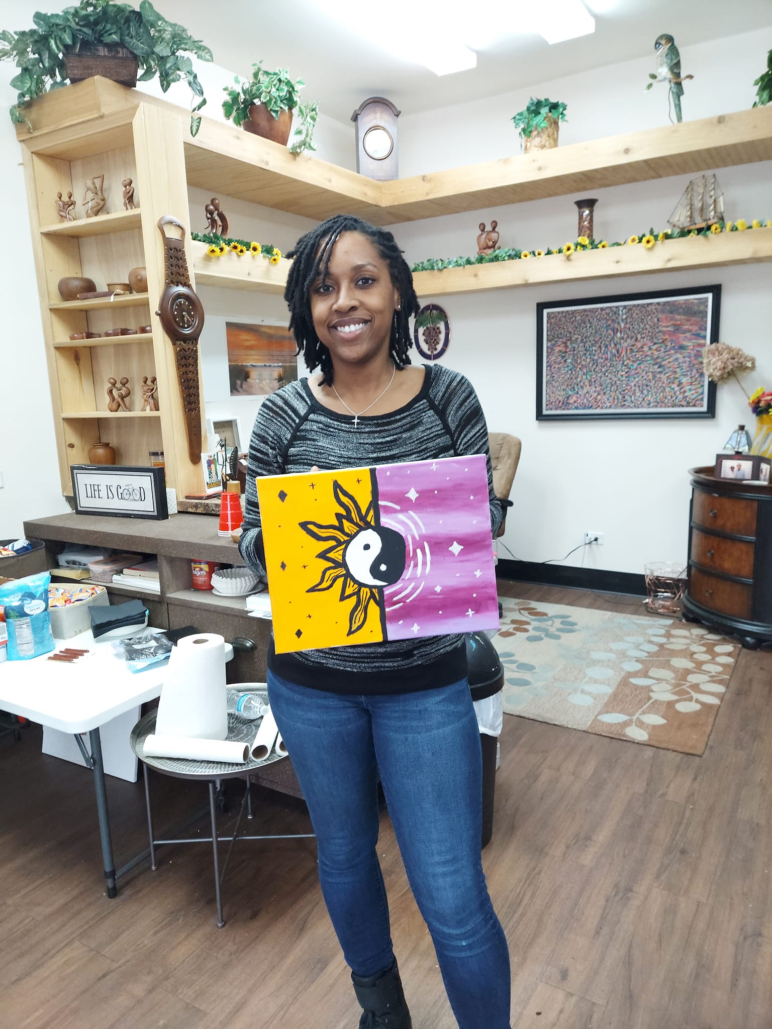 A woman is holding a painting in a room.