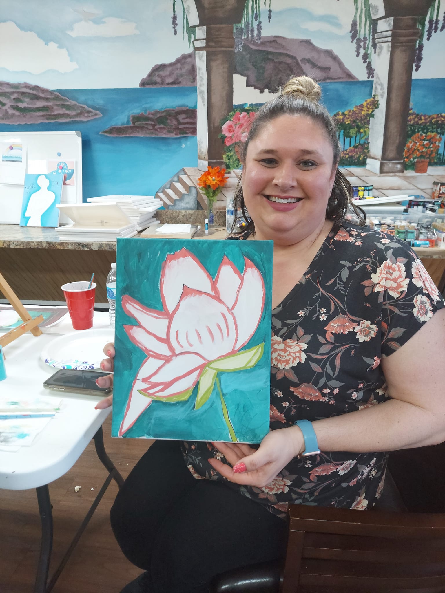 A woman is holding a painting of a lotus flower.