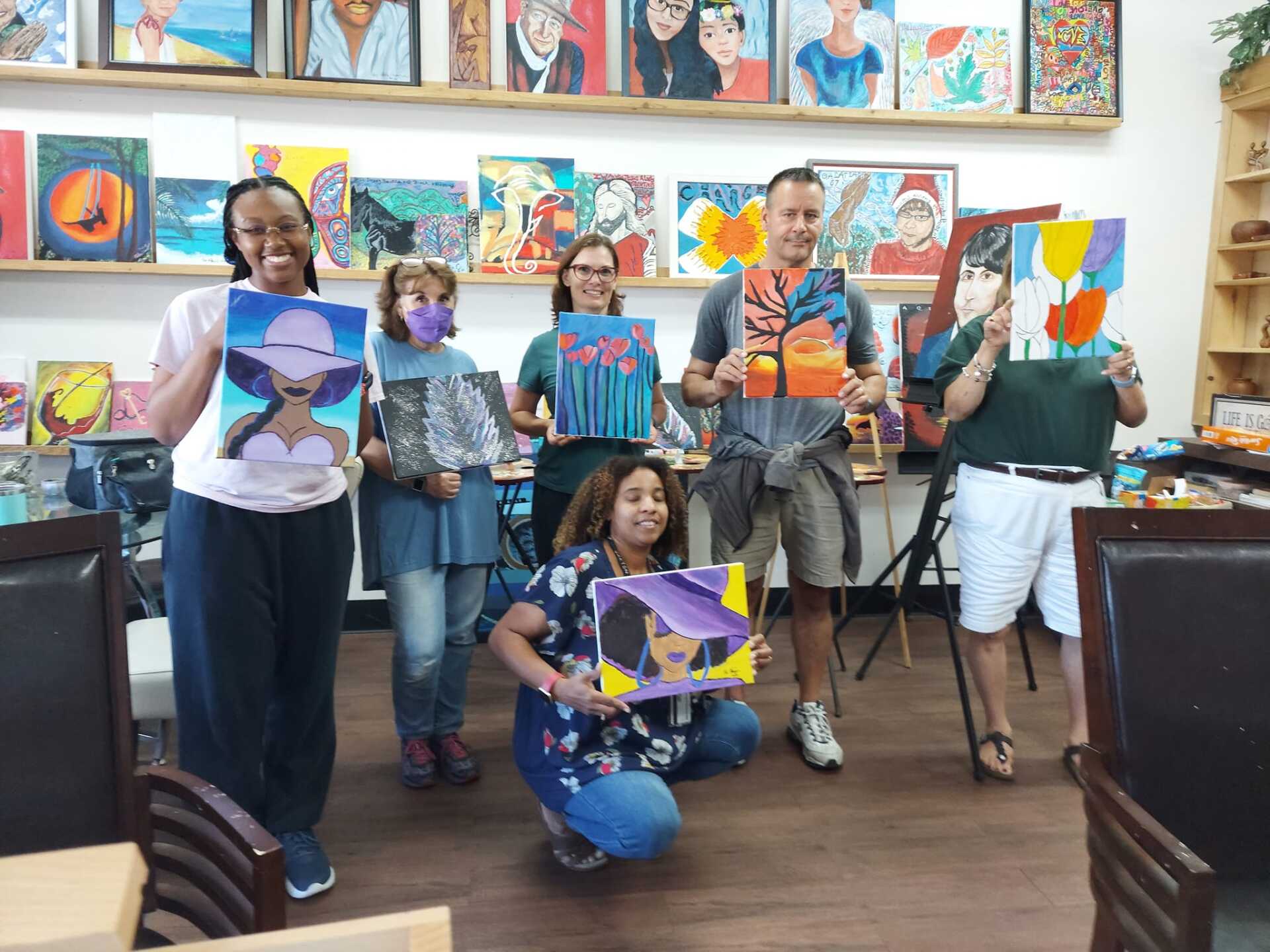 A group of people holding up paintings in a room