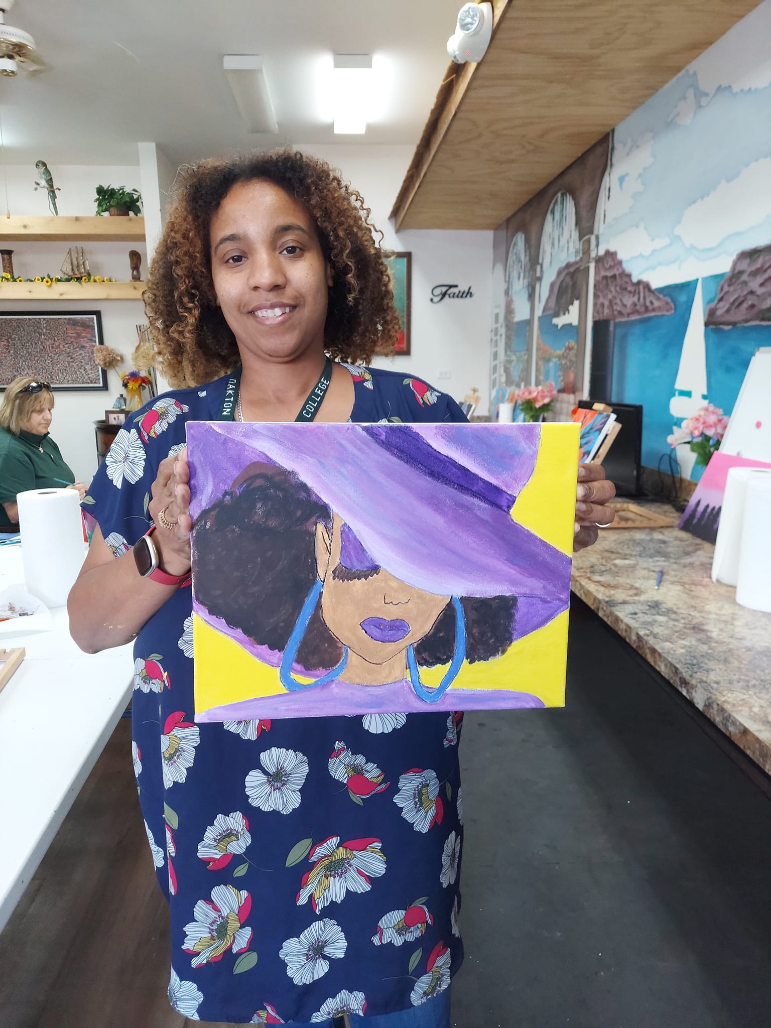 A woman is holding a painting of a woman wearing a purple hat and earrings.