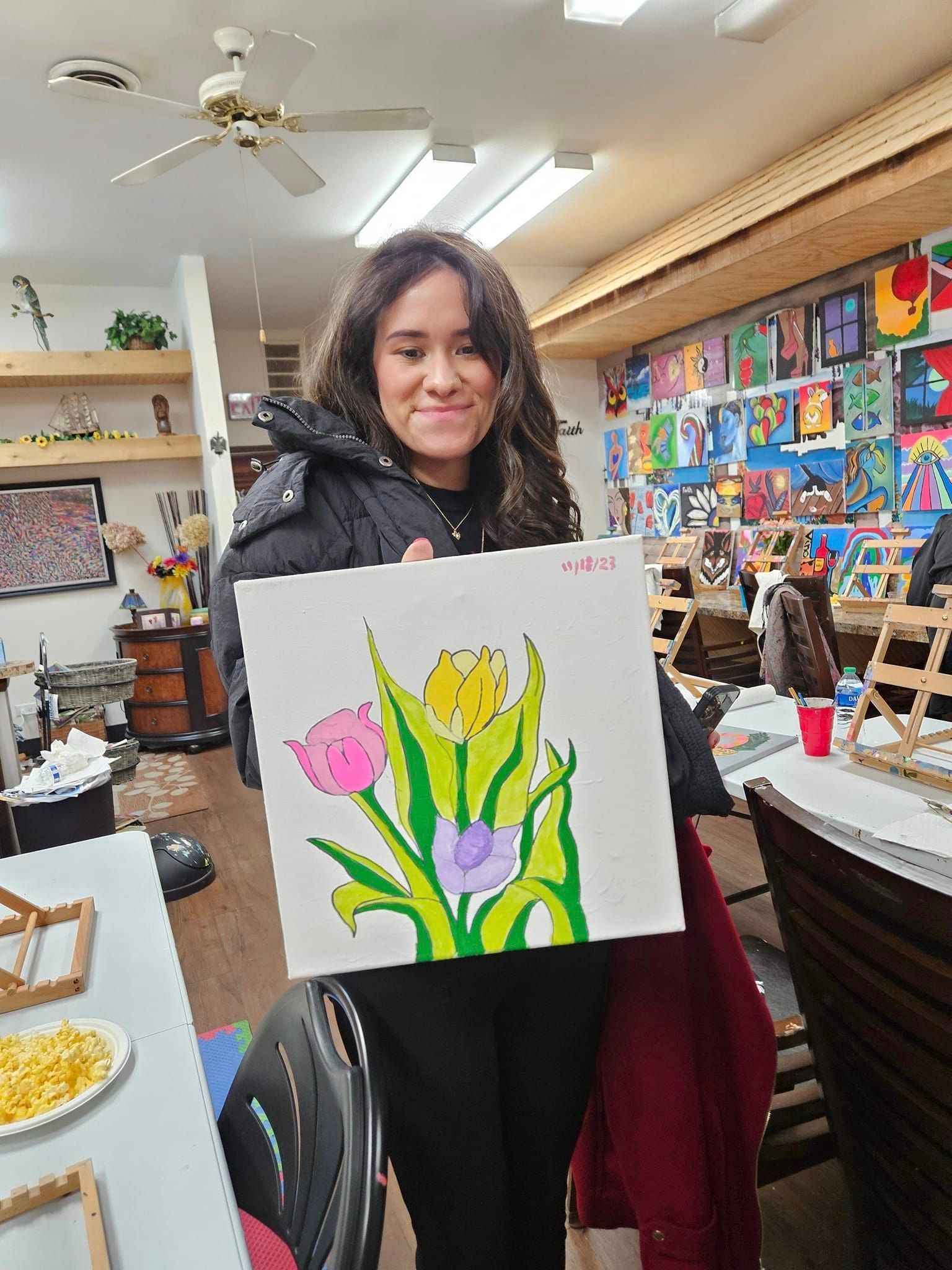 A woman is holding a painting of flowers in a room.