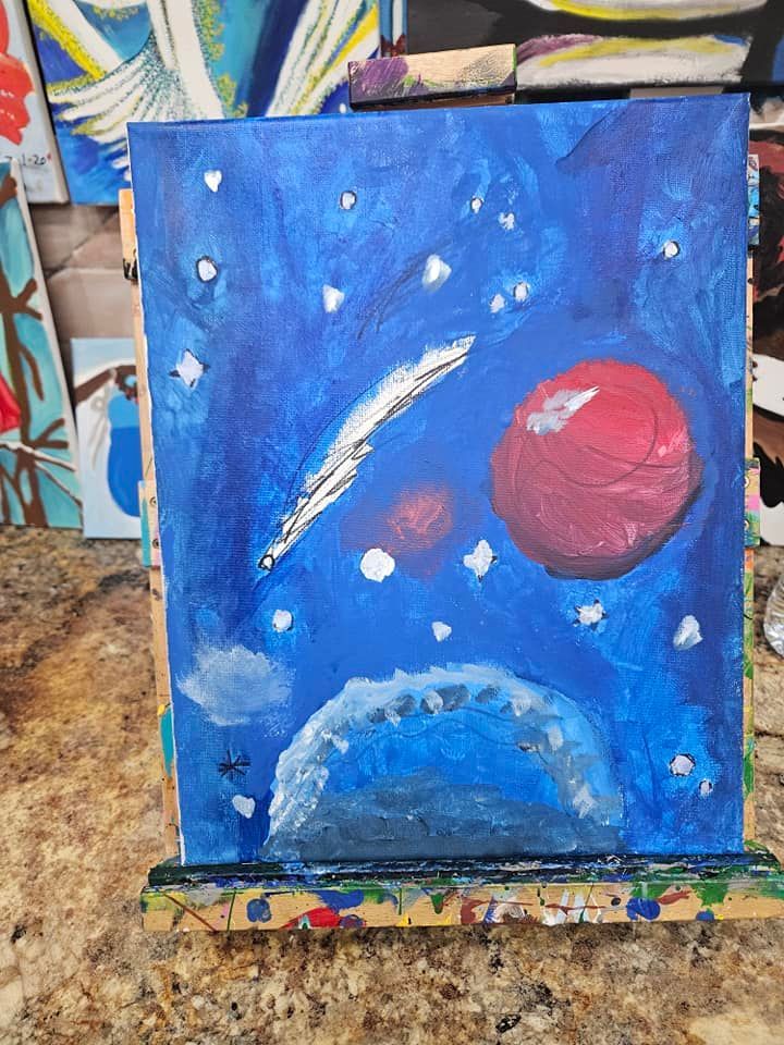 A painting of a planet in space is sitting on a wooden easel.