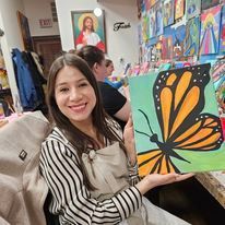 A woman is holding a painting of a butterfly in her hands.