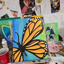 A painting of a butterfly on a canvas is sitting on a table.