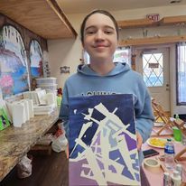 A young girl is holding a painting in her hands in a room.