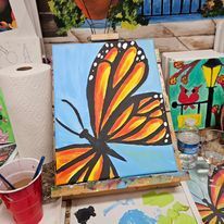 A painting of a butterfly on a canvas on an easel.