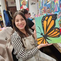 A woman is holding a painting of a butterfly in her hands.