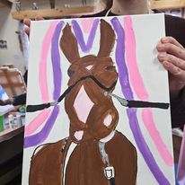 A person is holding a painting of a horse with a bridle.