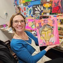 A woman is holding a painting of a woman 's face in her hands.