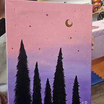 A person is holding a painting of a sunset with trees and a moon.