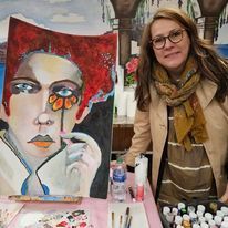 A woman is standing in front of a painting of a woman holding a flower.
