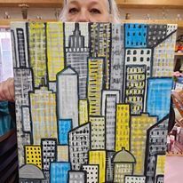 A woman is holding a painting of a city with buildings.