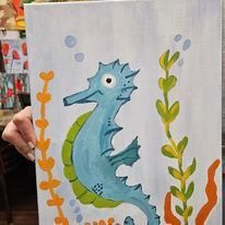 A person is holding a painting of a seahorse and seaweed.