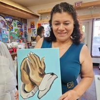 A woman is holding a painting of two hands clapping.