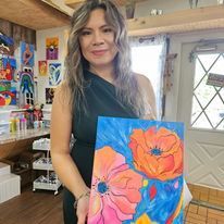 A woman is holding a painting of flowers in a room.