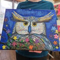 A person is holding a painting of an owl with flowers around its neck.