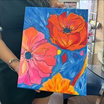 A woman is holding a painting of flowers on a blue background.