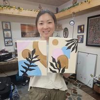 A woman is holding two paintings in her hands in a room.