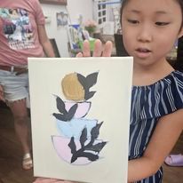 A little girl is holding a painting in her hands.