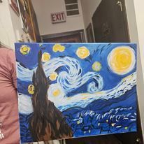 A person is holding a painting of the starry night by van gogh.