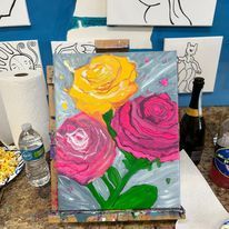 A painting of three roses on an easel on a table.