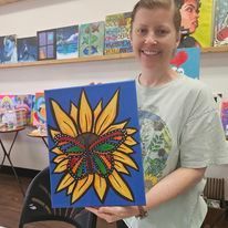 A woman is holding a painting of a sunflower with a butterfly on it.