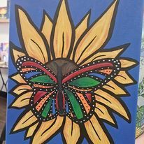 A colorful butterfly is sitting on top of a sunflower.