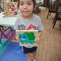 A little girl is holding a painting of a turtle.