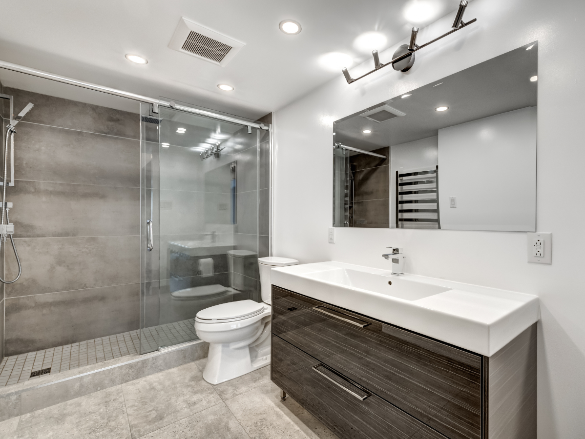 Modern bathroom with glass shower, toilet, and floating vanity with large mirror