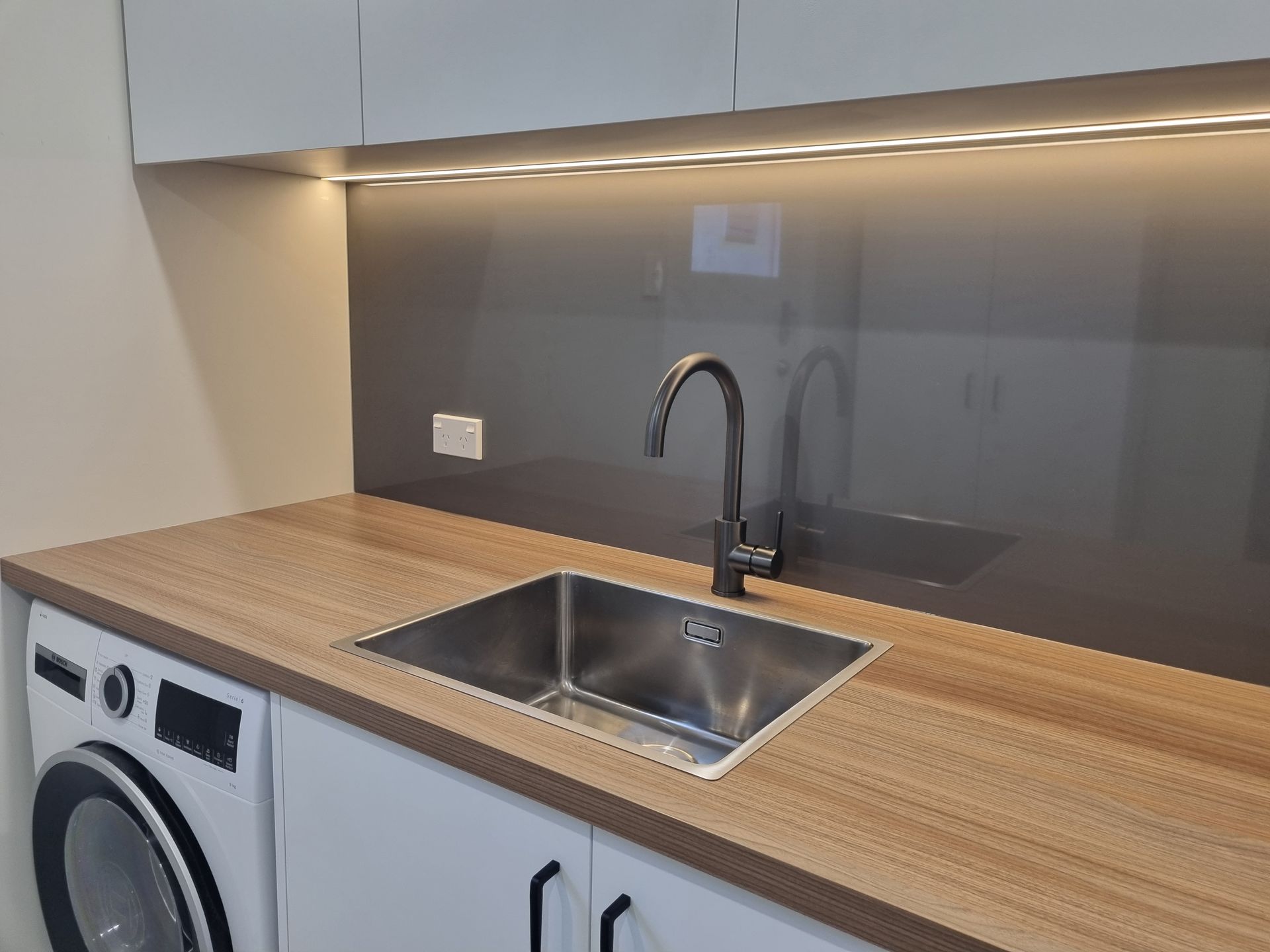 Completed Christchurch laundry with timber-look benchtop and DesignerSplash splashback