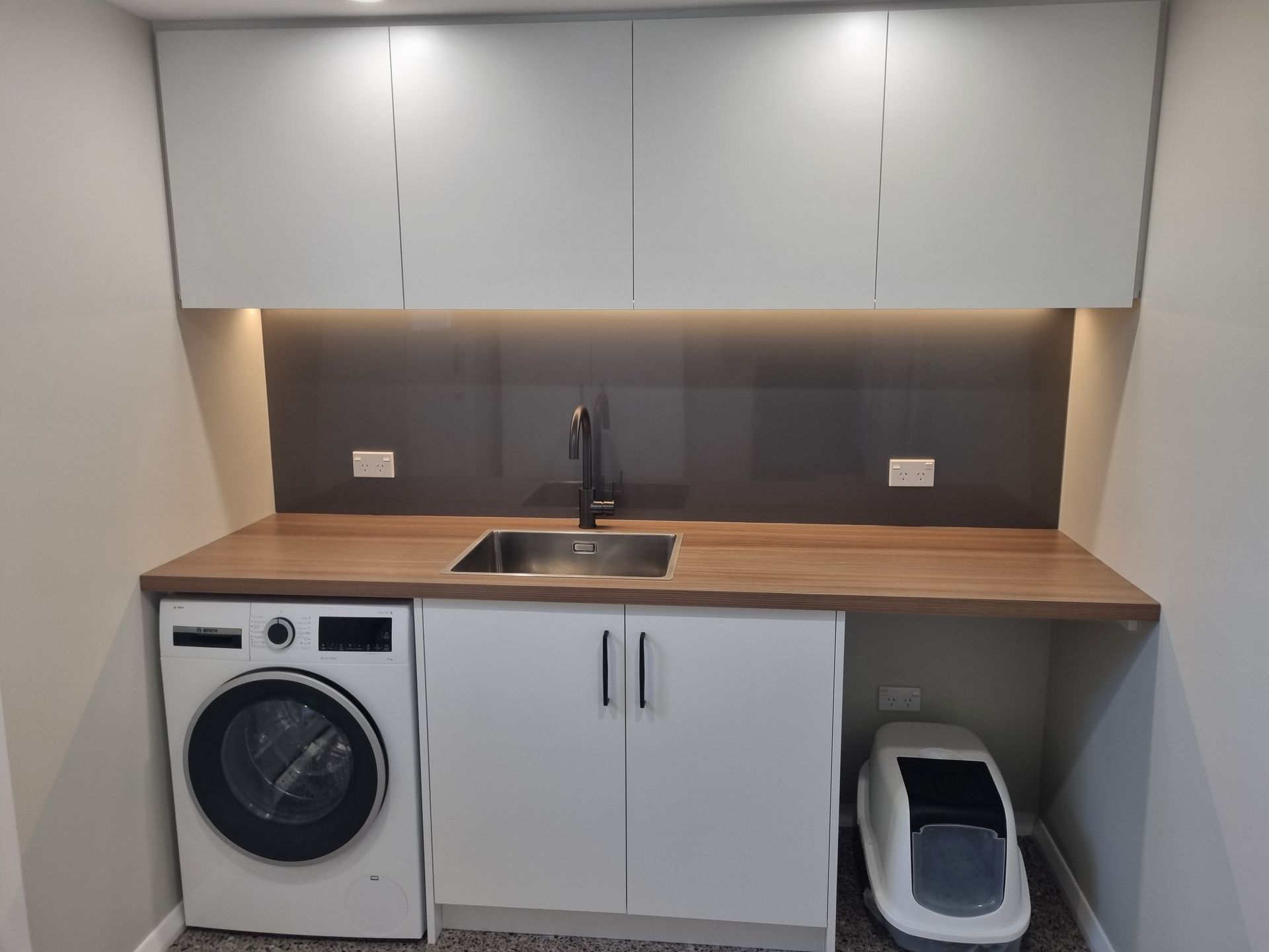 Detail of laundry sink, gunmetal mixer and overhead cabinetry