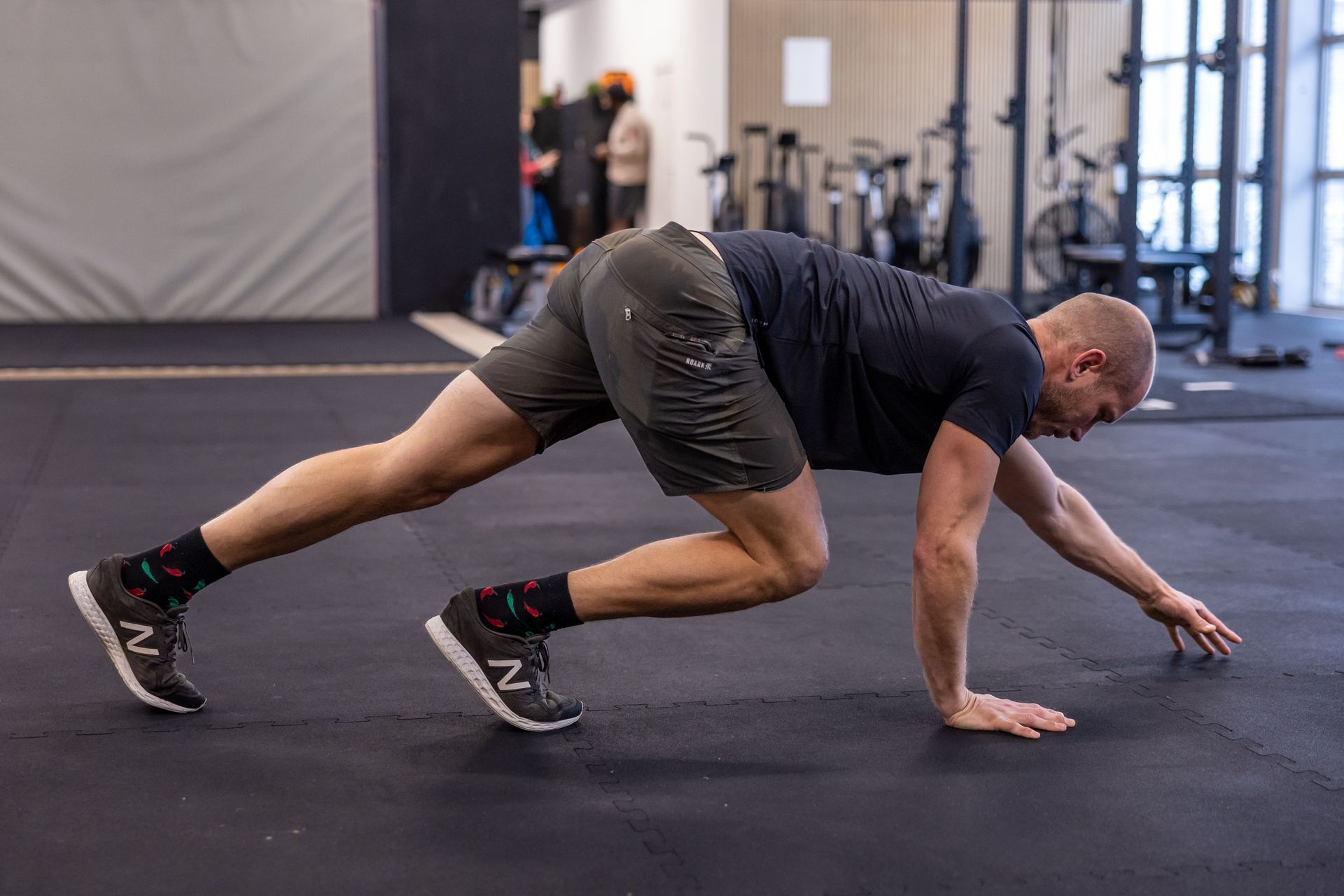A person in a gym in Winterthur performing a crawling exercise on a black mat, balancing on hands and feet