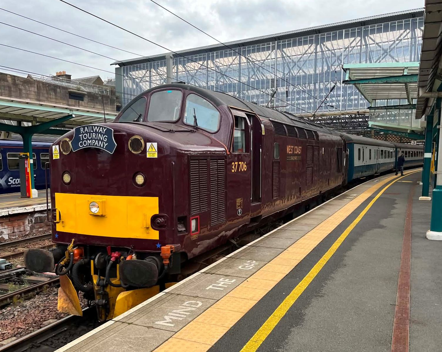 Maroon vintage train at a station platform under a glass canopy