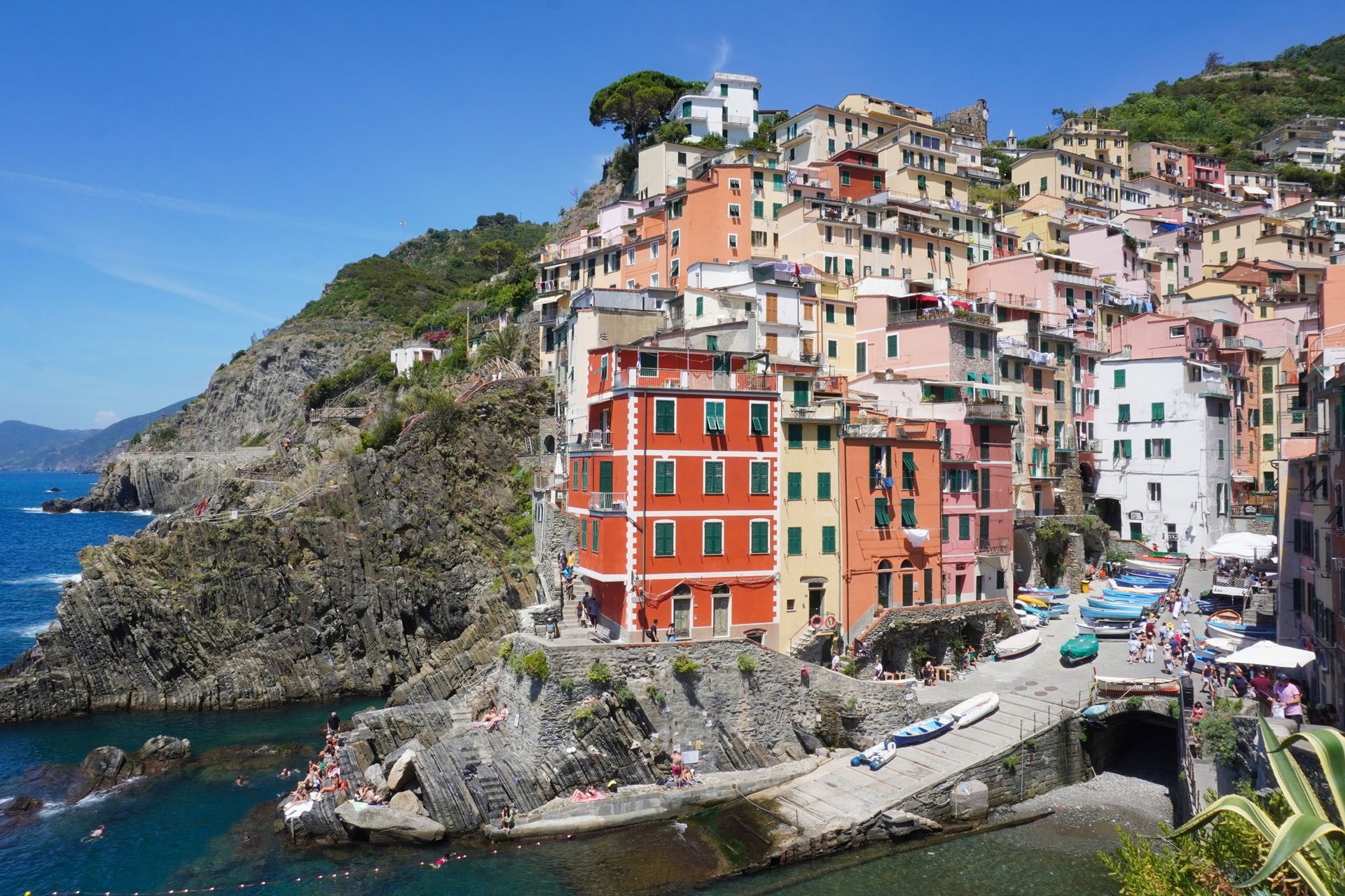 Colorful buildings cascade down a hillside to the sea in Riomaggiore, Italy.