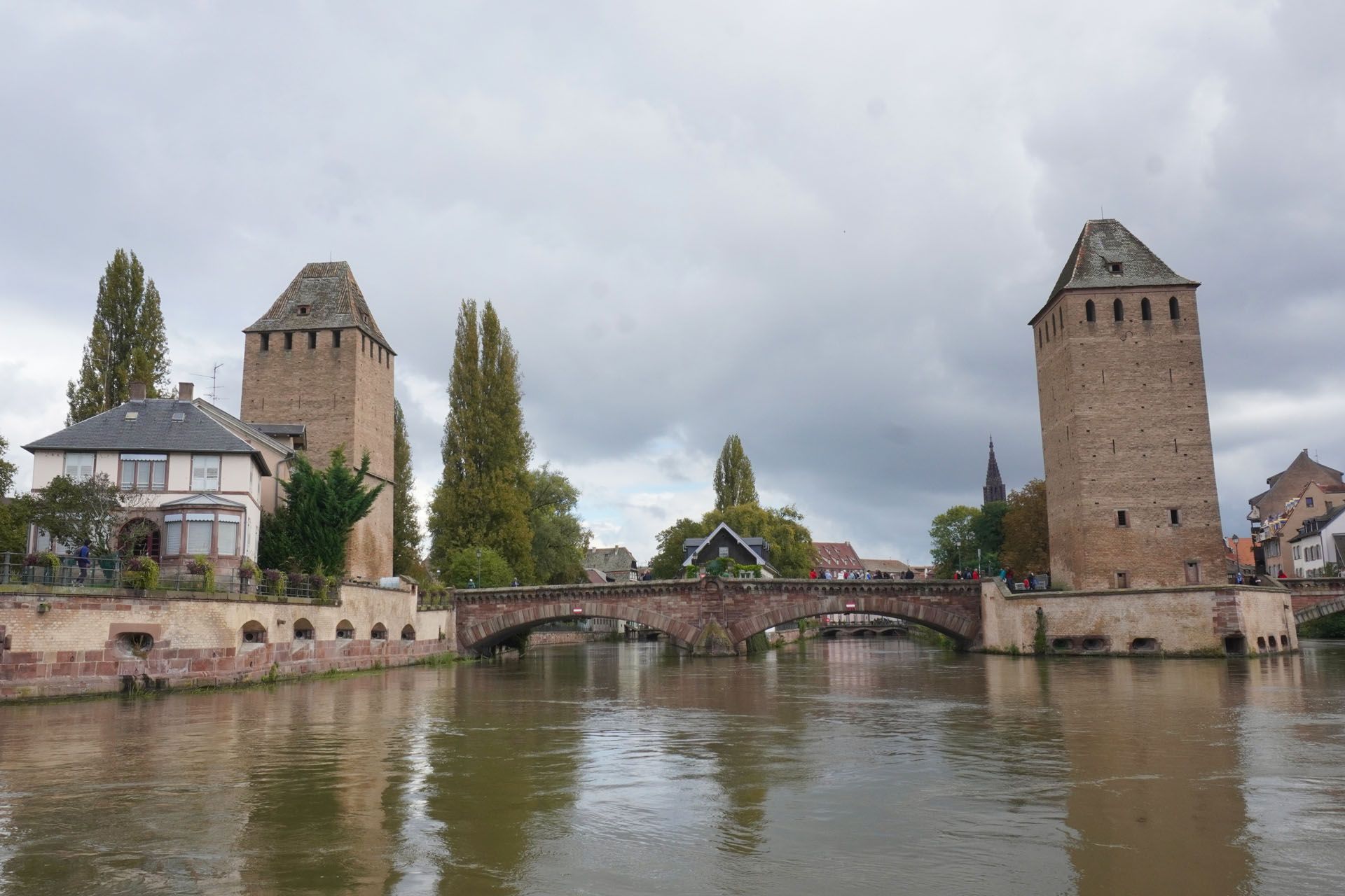 Towers of Ponts Couverts, Strasbourg, France, over a canal. Stone towers, arched bridge, cloudy sky.