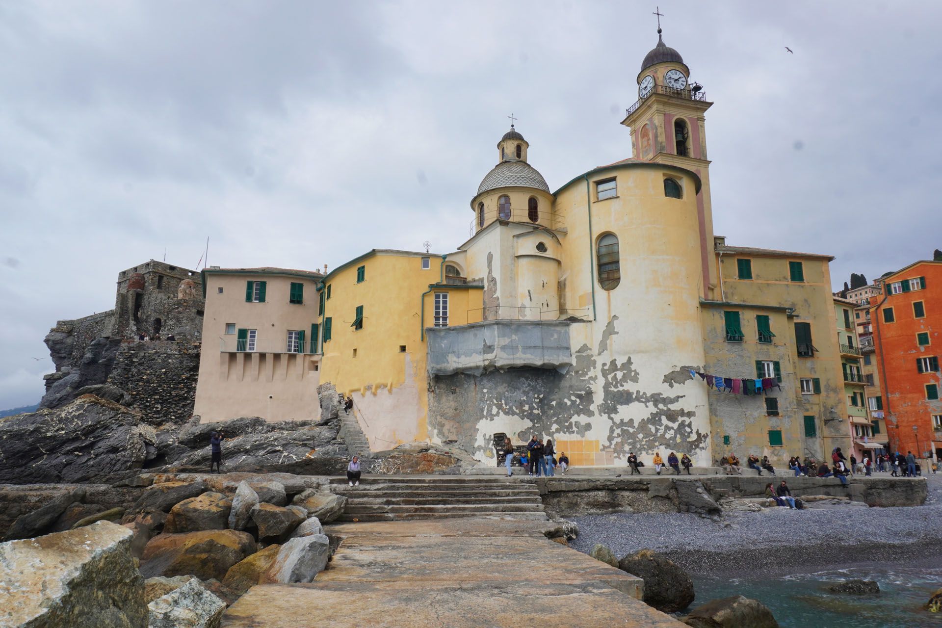 Coastal church with clock tower and colorful buildings, Camogli, Italy.