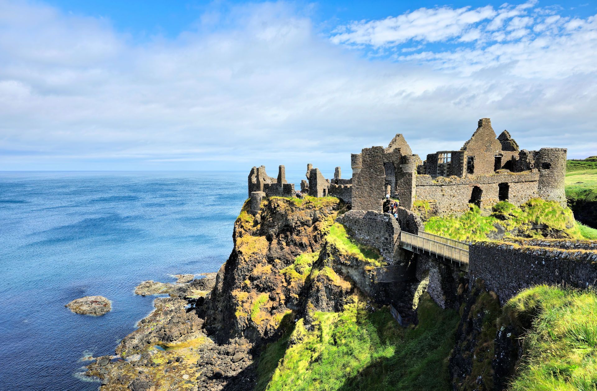 Ruins on a rocky seaside cliff under a blue sky, overlooking the ocean
