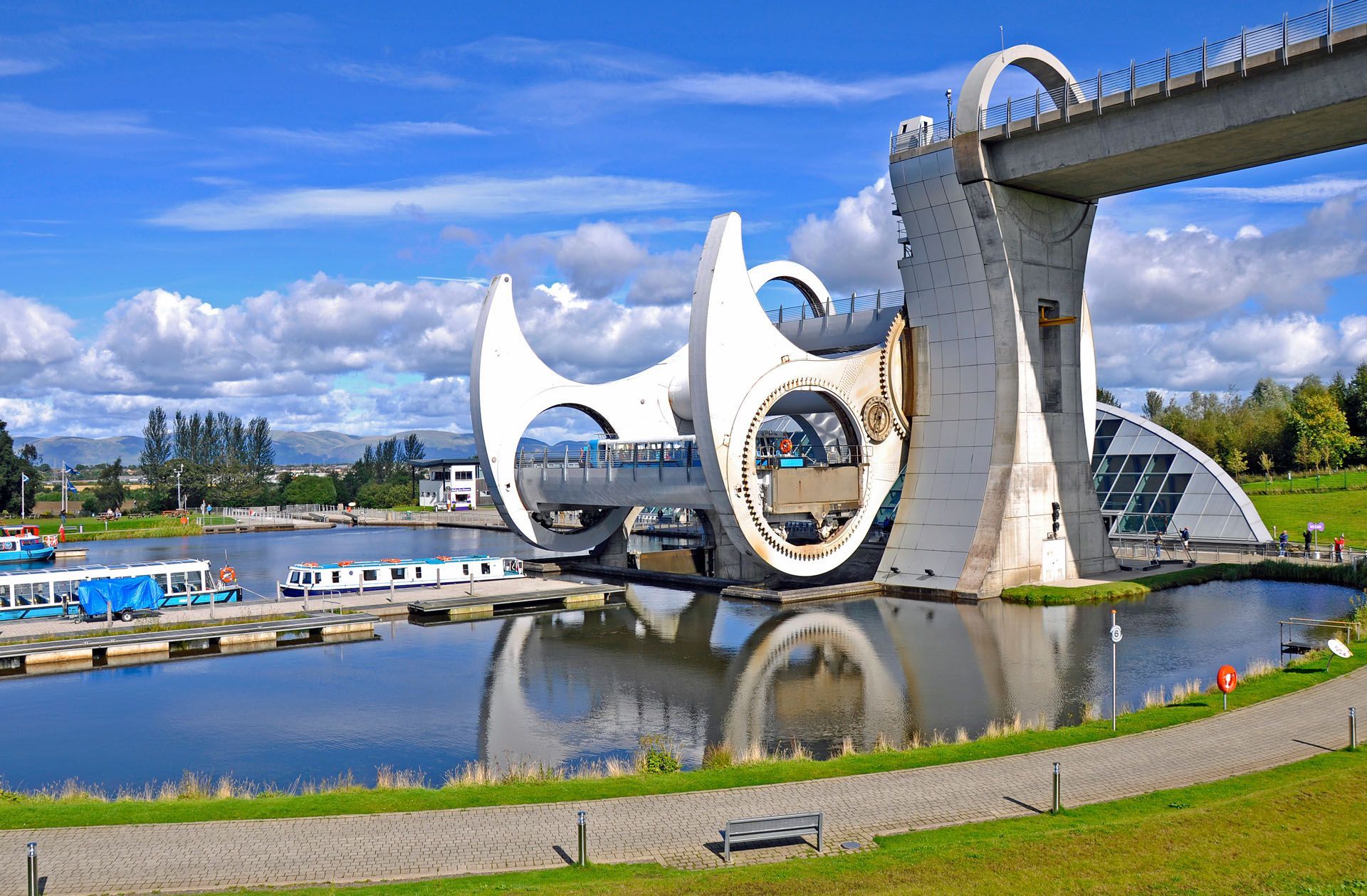 Futuristic rotating boat lift with water reflection beside a canal under a blue sky