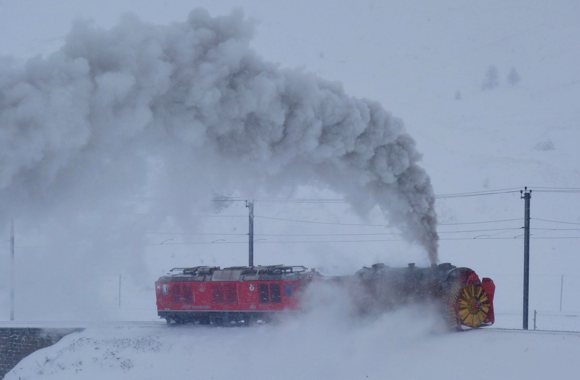 Red snowplow train blowing snow in a snowy landscape