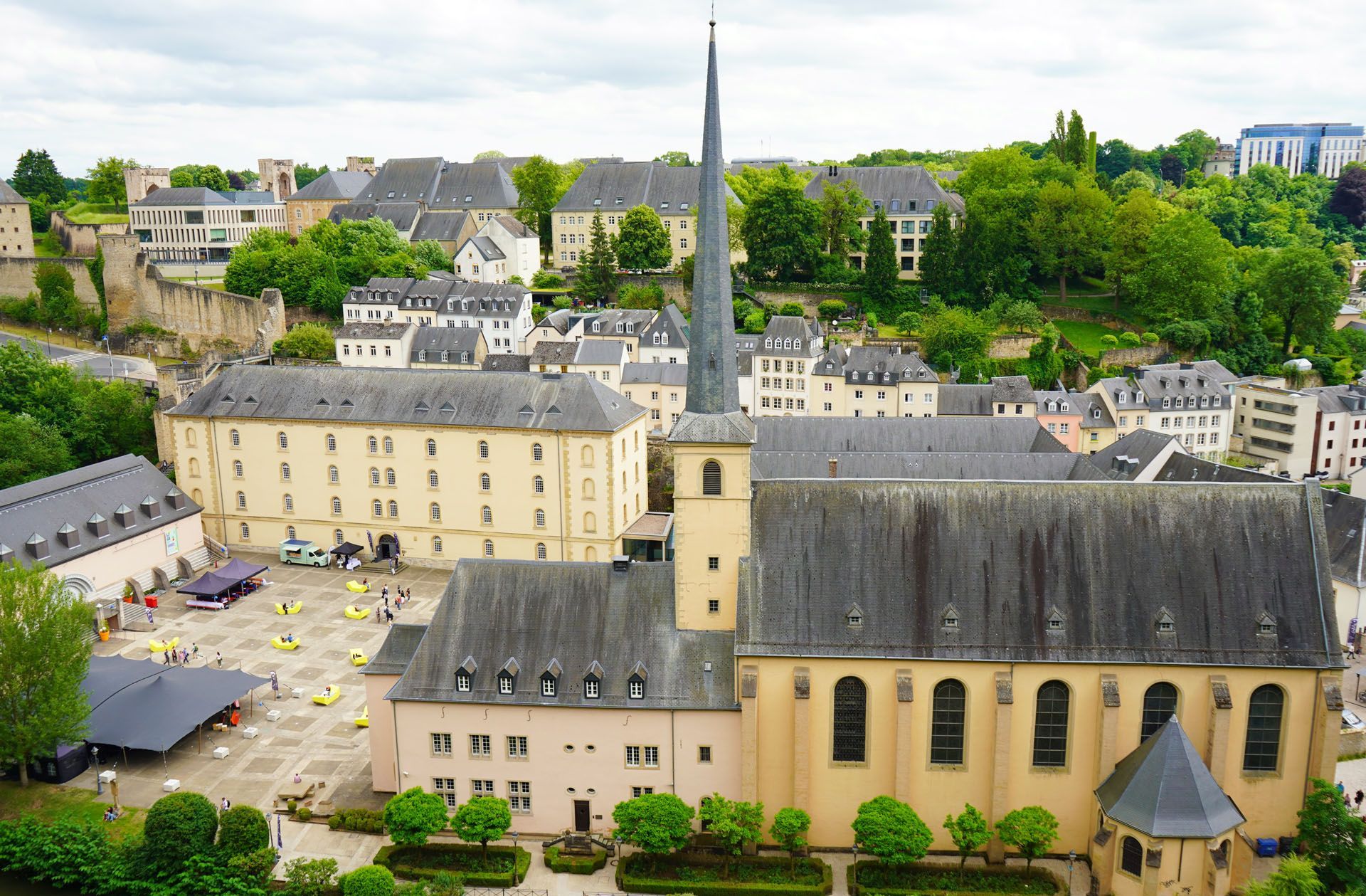 Aerial view of a beige church with a tall steeple in a green town square